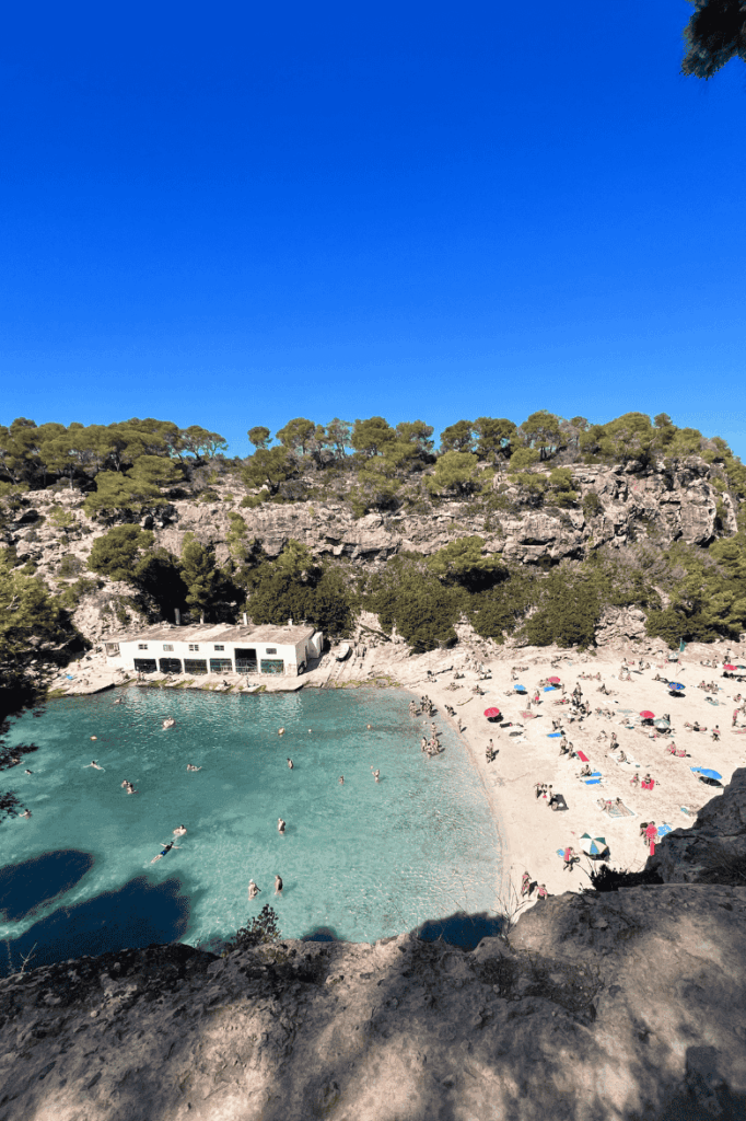 Cala Lombard beach covered with colorful umbrellas and aurrounded by turquoise water Mallorca travel guide