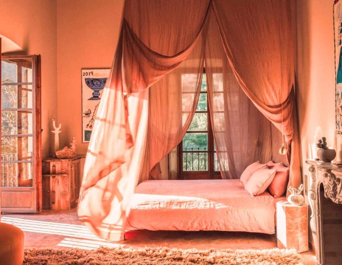 A coral pink hotel room with canopy bed at Hotel Corazon, which is on the list of the best Mallorca boutique hotels.